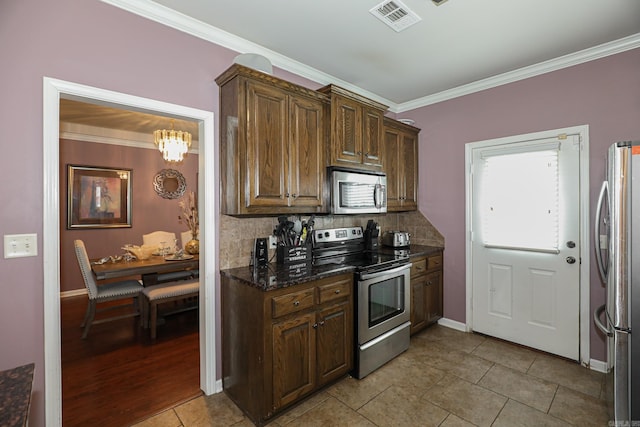 kitchen with stainless steel appliances, ornamental molding, dark stone countertops, light tile patterned floors, and decorative backsplash