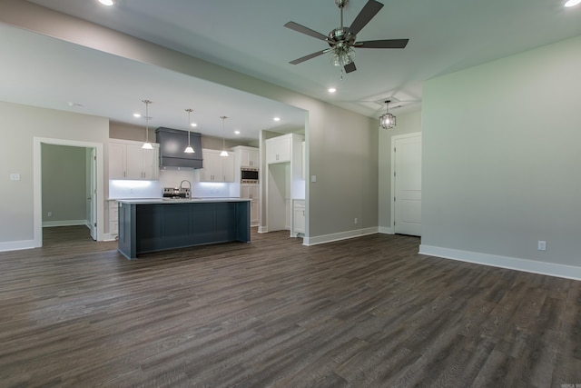 kitchen featuring ceiling fan, hanging light fixtures, a kitchen island with sink, white cabinets, and dark hardwood / wood-style flooring