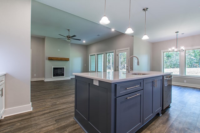 kitchen with decorative light fixtures, sink, dark hardwood / wood-style floors, and a kitchen island with sink