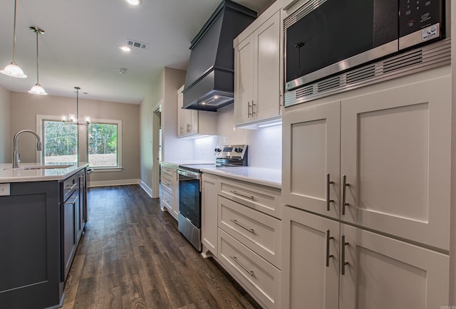 kitchen featuring appliances with stainless steel finishes, decorative light fixtures, dark hardwood / wood-style floors, sink, and white cabinets