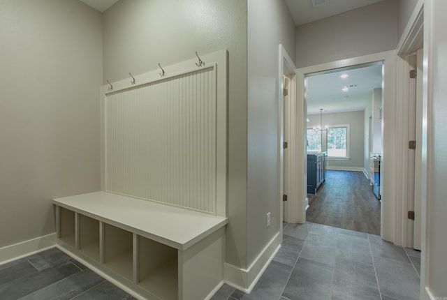 mudroom with dark hardwood / wood-style floors and an inviting chandelier