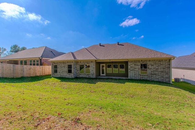 back of property with central AC unit and a lawn