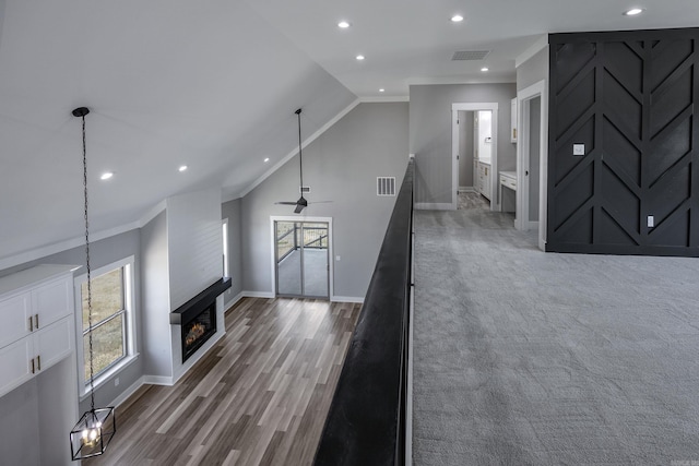 unfurnished living room with lofted ceiling, hardwood / wood-style floors, ceiling fan, crown molding, and a large fireplace