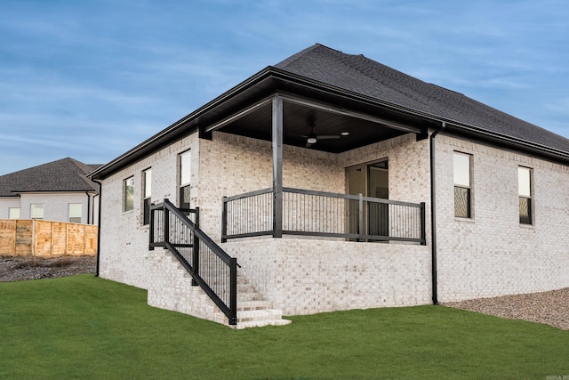 view of side of property with ceiling fan and a yard