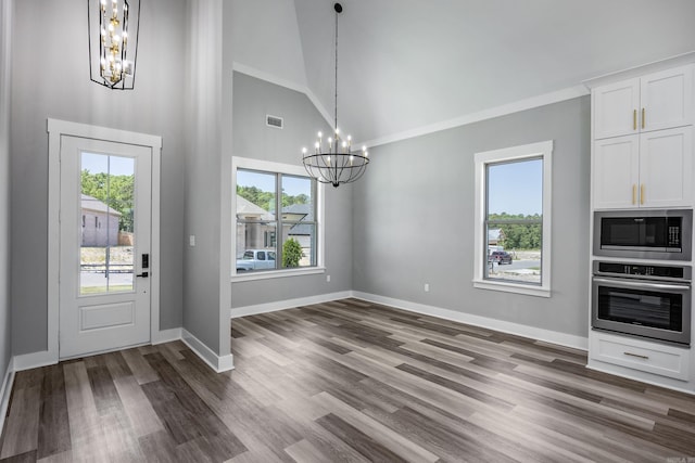 foyer entrance featuring dark hardwood / wood-style floors, a chandelier, high vaulted ceiling, and ornamental molding