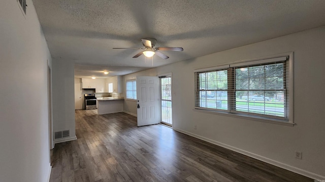 unfurnished living room with dark hardwood / wood-style flooring, a textured ceiling, and ceiling fan