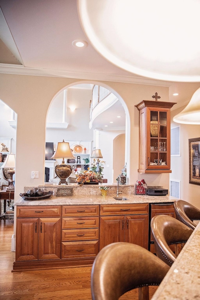 bar with crown molding, hardwood / wood-style floors, sink, and light stone counters