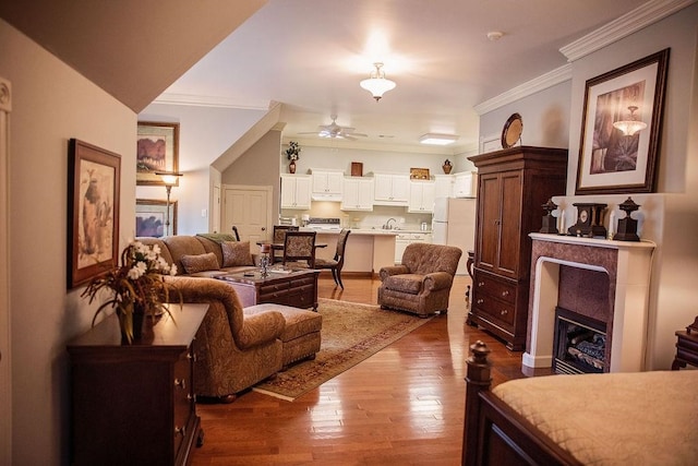 living room with sink, ceiling fan, hardwood / wood-style floors, and ornamental molding