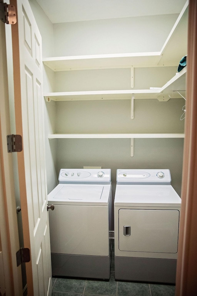 laundry room with washer and dryer and dark tile patterned floors