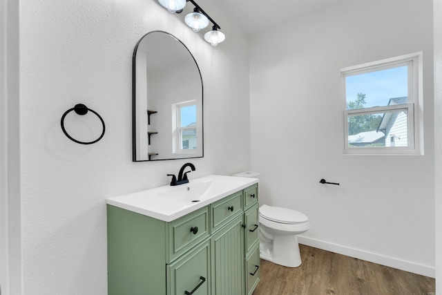 bathroom with hardwood / wood-style floors, vanity, a healthy amount of sunlight, and toilet