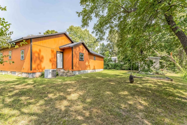 exterior space featuring central air condition unit and a yard