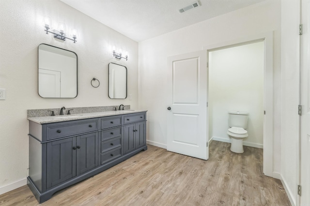 bathroom with wood-type flooring, a textured ceiling, toilet, and vanity