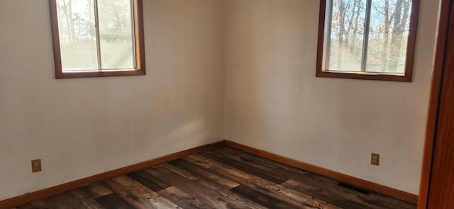 spare room with dark hardwood / wood-style floors and a wealth of natural light