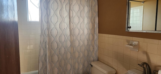 bathroom with walk in shower, toilet, and tile walls