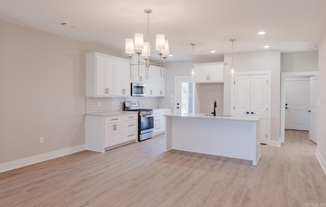 kitchen featuring stainless steel appliances, white cabinetry, pendant lighting, and a kitchen island with sink