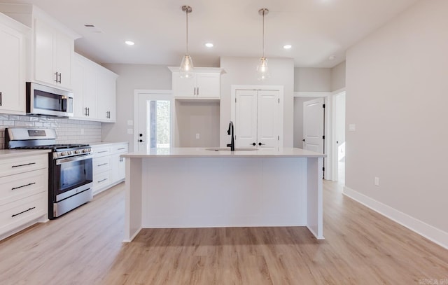 kitchen featuring an island with sink, white cabinets, and appliances with stainless steel finishes