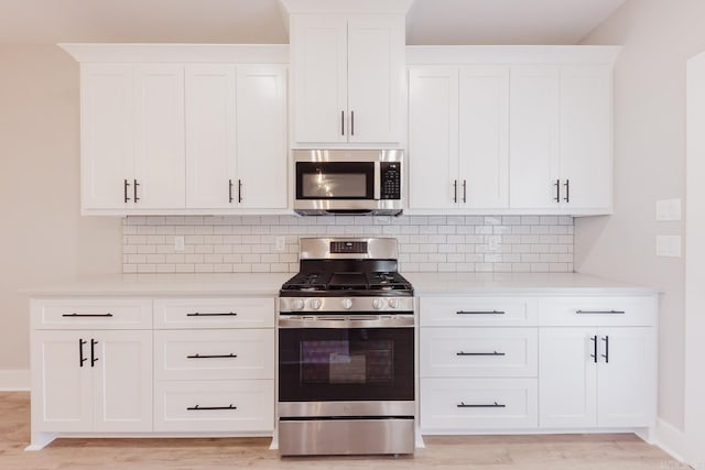 kitchen featuring white cabinets, appliances with stainless steel finishes, light hardwood / wood-style floors, and tasteful backsplash