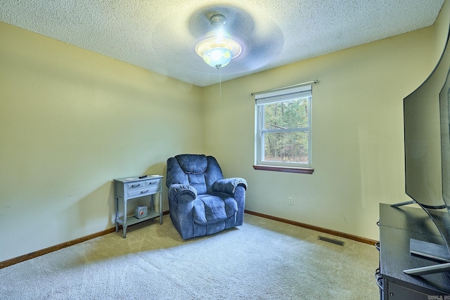 living area featuring a textured ceiling, light carpet, and ceiling fan