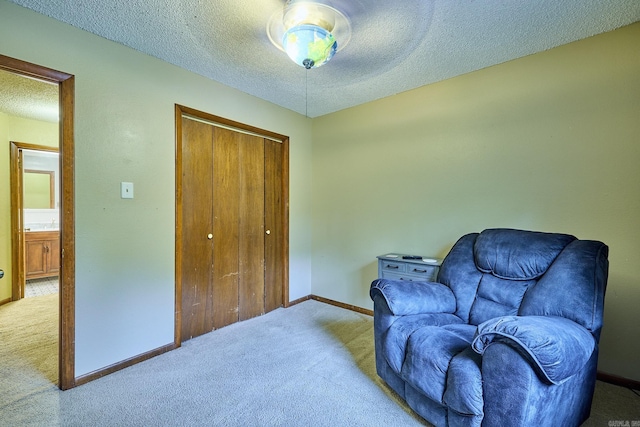 sitting room featuring light colored carpet and a textured ceiling