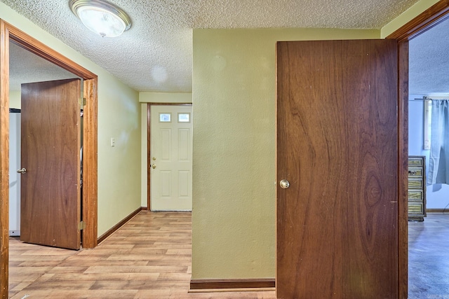 hall featuring a textured ceiling and light hardwood / wood-style flooring