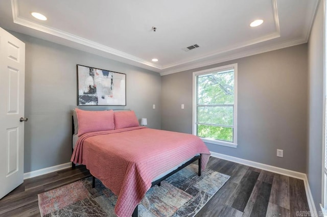 bedroom featuring ornamental molding, dark wood-type flooring, and a raised ceiling