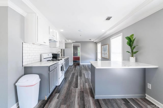 kitchen with white range with gas cooktop, kitchen peninsula, white cabinets, and dark hardwood / wood-style floors