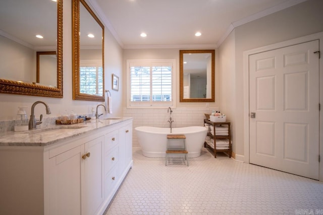 bathroom with a bath, vanity, tile walls, and ornamental molding