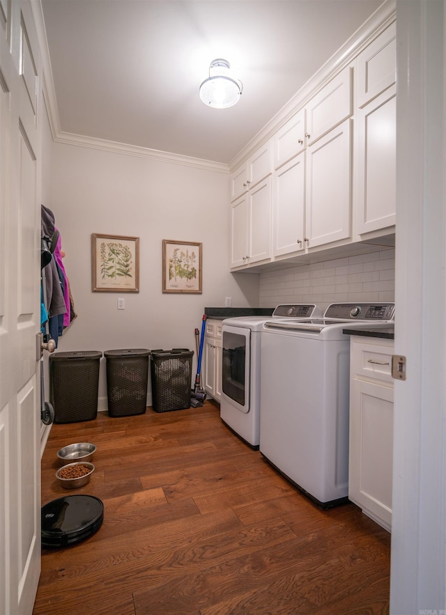 clothes washing area with ornamental molding, dark wood-type flooring, cabinets, and washing machine and dryer