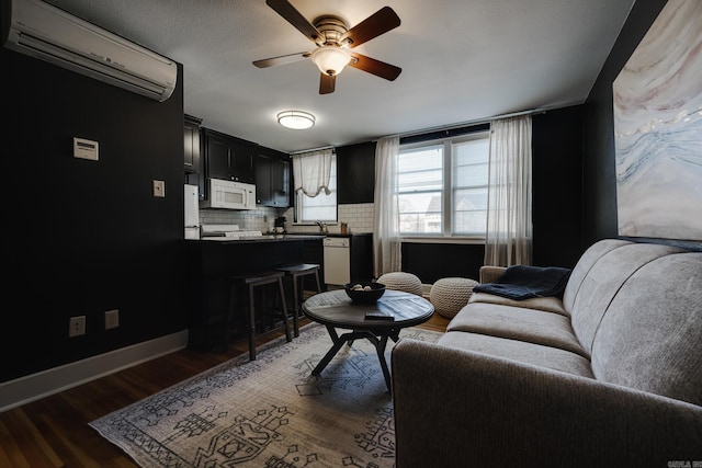 living room featuring dark hardwood / wood-style flooring, a wall unit AC, sink, and ceiling fan