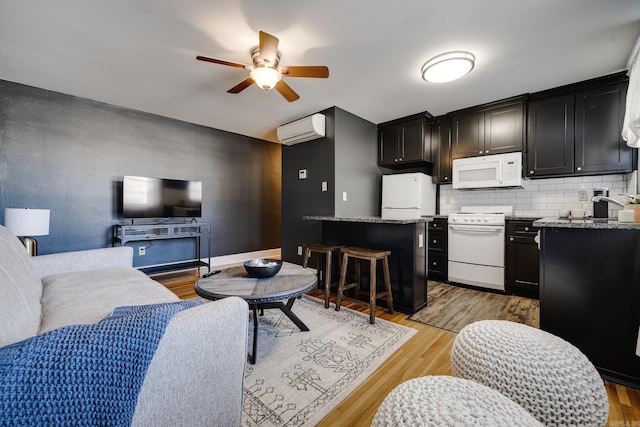 kitchen with a kitchen bar, decorative backsplash, light hardwood / wood-style flooring, white appliances, and a wall mounted air conditioner