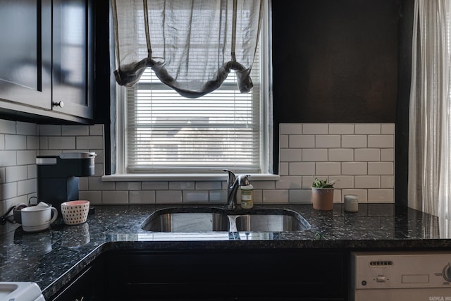 kitchen featuring dark stone countertops, tasteful backsplash, sink, and washer / dryer