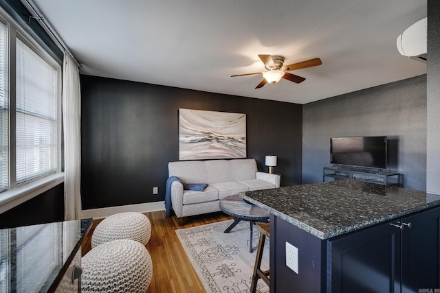 living room with ceiling fan, dark hardwood / wood-style flooring, and a wall mounted air conditioner