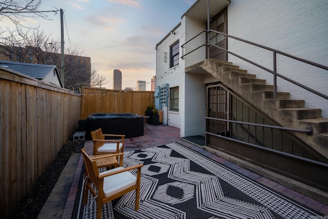 patio terrace at dusk featuring a hot tub