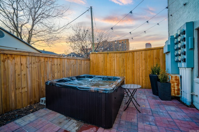 patio terrace at dusk featuring a hot tub