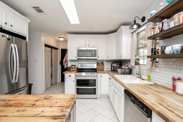 kitchen featuring sink, white cabinets, stainless steel appliances, and wood counters