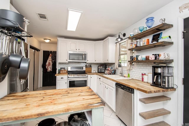 kitchen featuring butcher block countertops, tasteful backsplash, appliances with stainless steel finishes, sink, and white cabinets