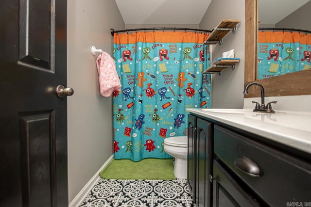 bathroom with tile patterned floors, vanity, toilet, and lofted ceiling