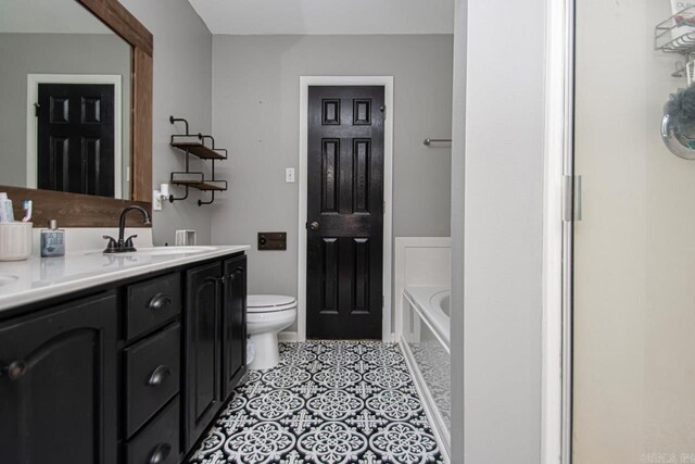 bathroom with tile patterned floors, vanity, a tub to relax in, and toilet