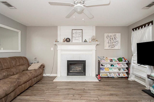 living room featuring a tiled fireplace, hardwood / wood-style floors, and ceiling fan