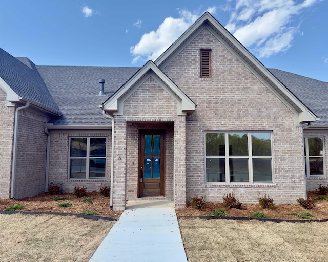 view of front of home with a shingled roof and brick siding