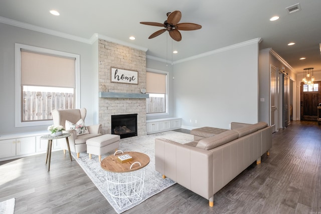 living room featuring dark wood-type flooring, a fireplace, ceiling fan, and ornamental molding