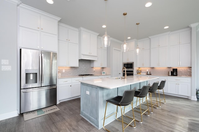 kitchen featuring sink, appliances with stainless steel finishes, a breakfast bar area, wood-type flooring, and white cabinets