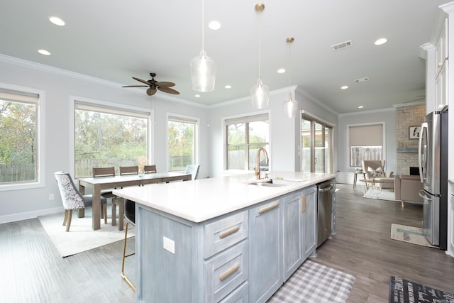 kitchen with a wealth of natural light, sink, decorative light fixtures, and an island with sink