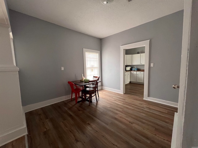 dining space with dark wood-type flooring and a textured ceiling