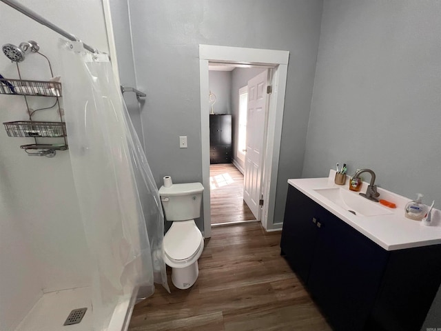 bathroom with hardwood / wood-style floors, walk in shower, vanity, and toilet