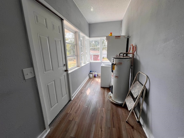 interior space featuring hardwood / wood-style flooring, water heater, a textured ceiling, and washer / dryer