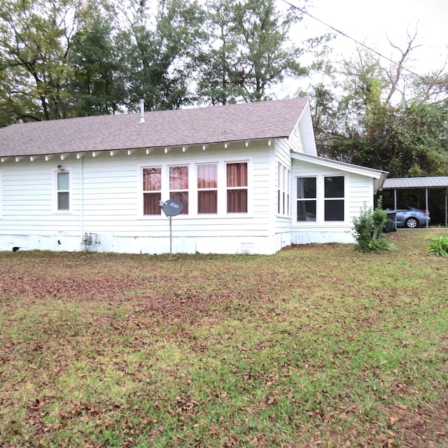 view of side of home with a yard and a carport