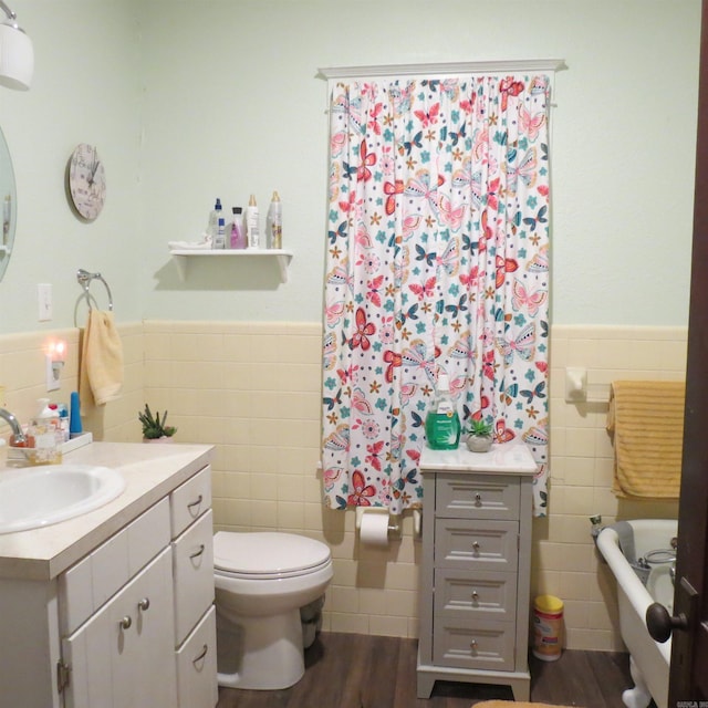 bathroom featuring wood-type flooring, vanity, toilet, and tile walls