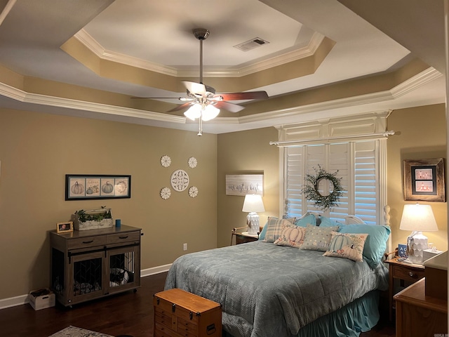 bedroom featuring dark wood-type flooring, ceiling fan, crown molding, and a tray ceiling