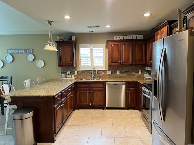 kitchen featuring appliances with stainless steel finishes, pendant lighting, sink, a kitchen breakfast bar, and kitchen peninsula